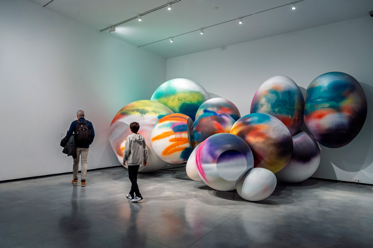 Visitantes contemplan una instalación escultórica de grandes formas circulares y colores en el Museo Helga de Alvear de Cáceres